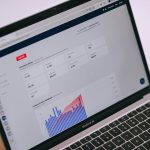 Analytics dashboard on a MacBook Air screen with charts and metric tiles, showing a blue bar chart in the lower section.