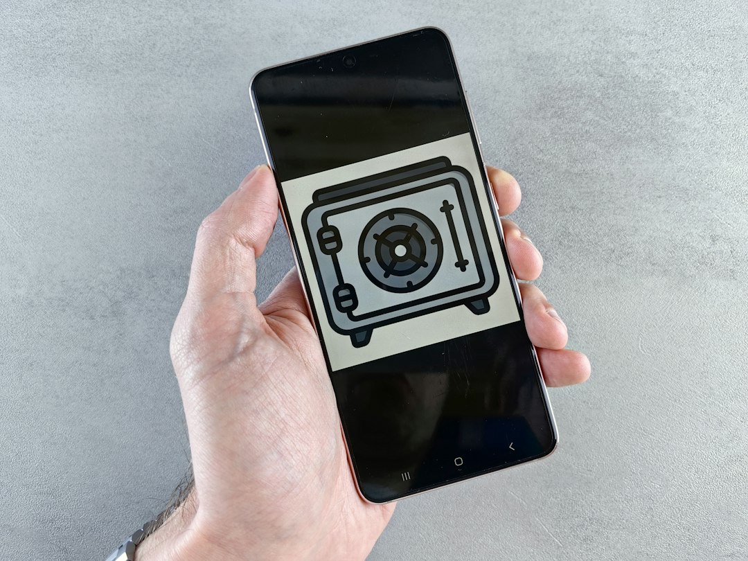 Hand holding a smartphone displaying a drawing of a safe on the screen.