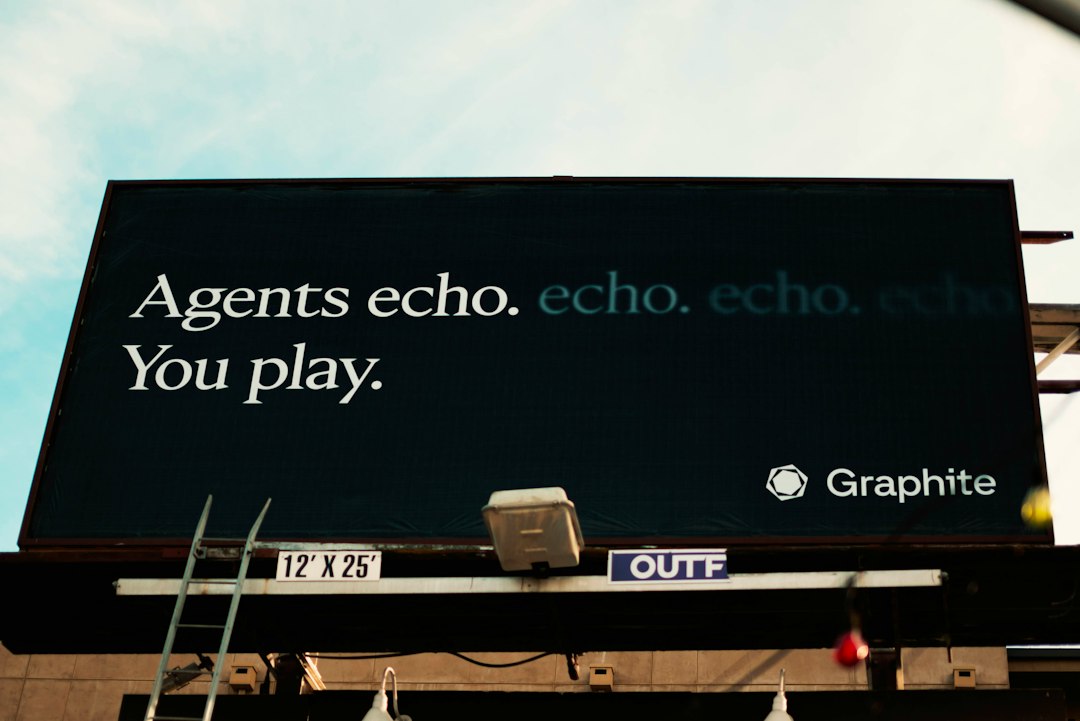 Outdoor billboard reads 'Agents echo. You play.' with a Graphite logo in the bottom right against a blue sky, seen from street level. Stratified by a ladder and equipment below.
