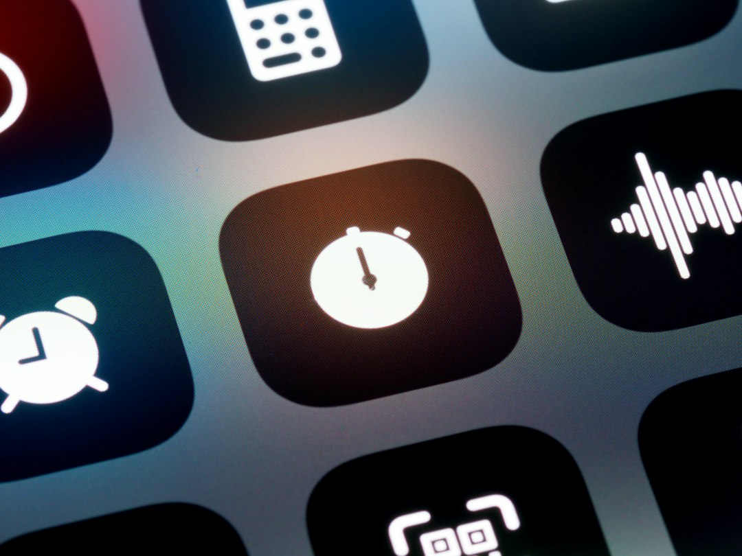 Close-up of a smartphone home screen with a white stopwatch icon in the center tile.