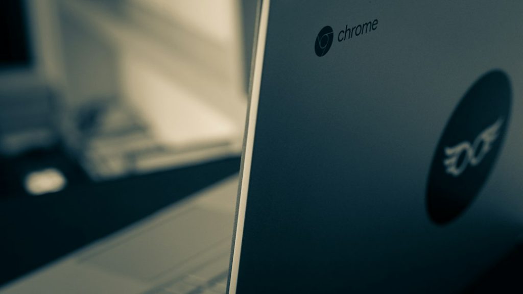 Close-up of a laptop lid showing the Chrome logo on a blue-tinged surface.