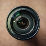 Top-down view of a Canon EF lens, 24-105mm, sits on a brown surface, glass elements reflecting light