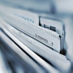 Stack of manila folders in a filing drawer labeled 'CLASSIFIED'.