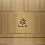 Wood-paneled wall with a black Genius Bar logo and the words ‘Genius Bar’ beneath it.