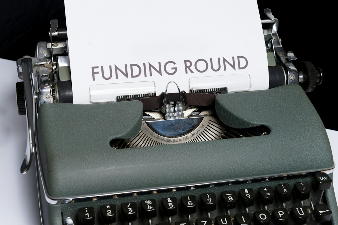 Green vintage typewriter typing a sheet that reads 'FUNDING ROUND' in bold letters.