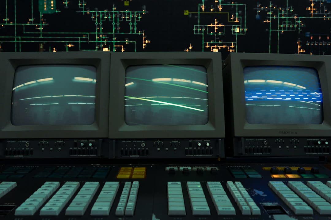 Retro computer console with three CRT monitors and a control panel, neon circuit board backdrop.