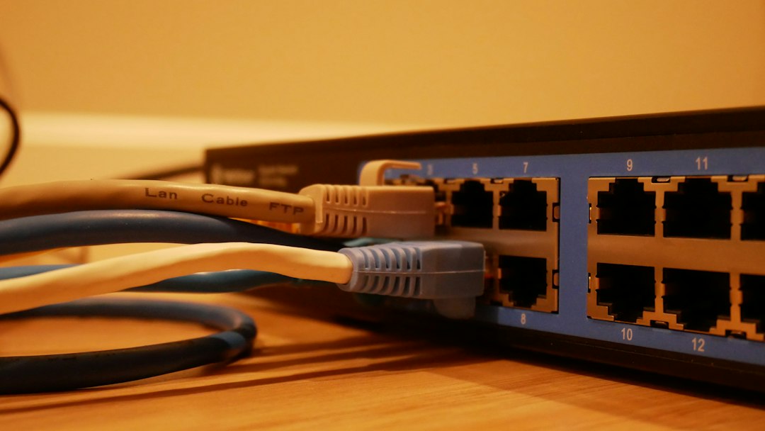 Blue network switch with multiple Ethernet cables plugged into ports labeled 5–12 on the front panel.