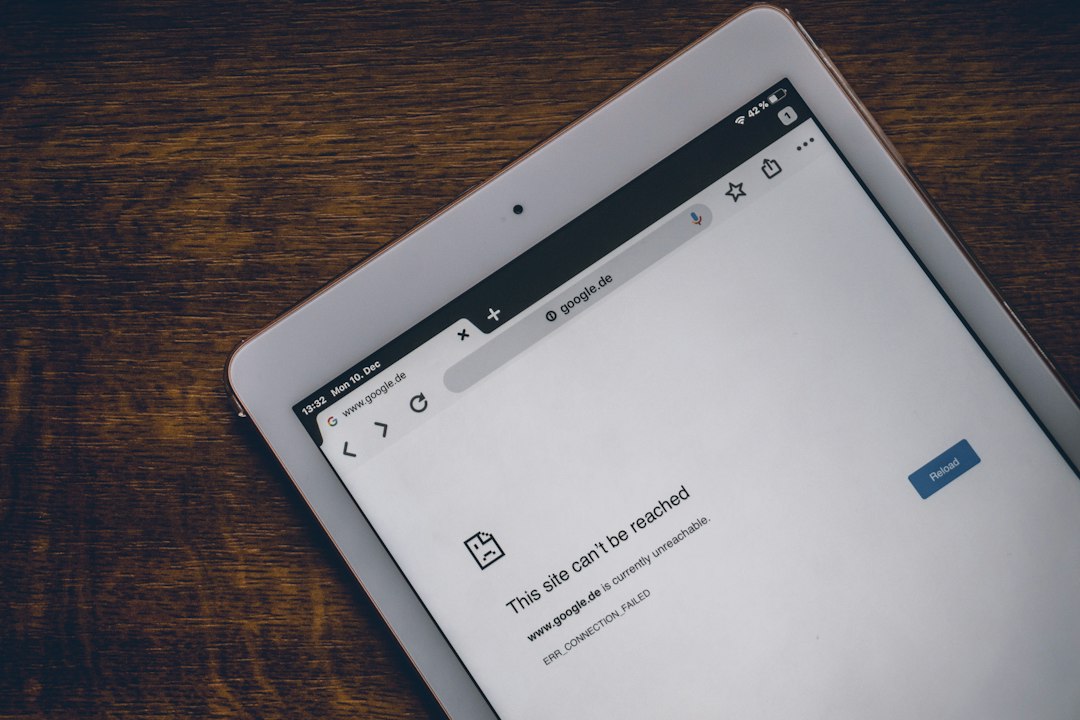 Tablet on a wooden desk displaying a 'This site can't be reached' browser error with a Reload button.